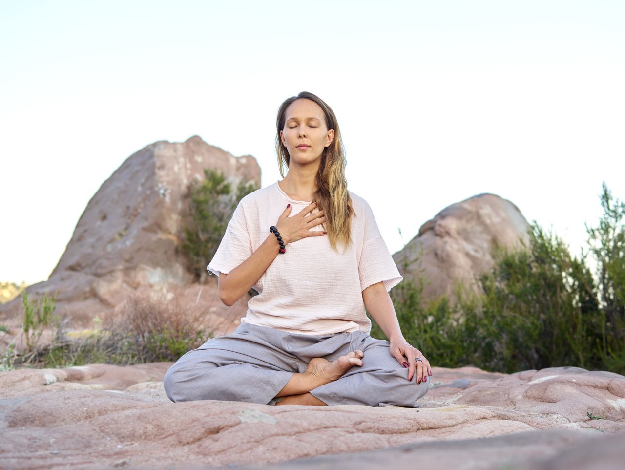Woman meditating outdoors with closed eyes, embodying peace and relaxation.